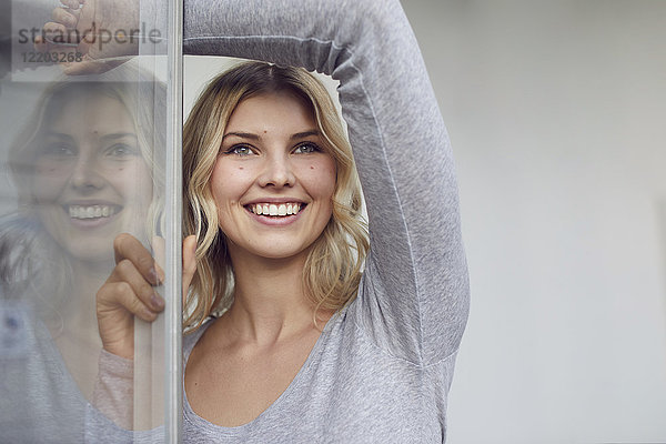 Porträt einer glücklichen Frau am offenen Fenster