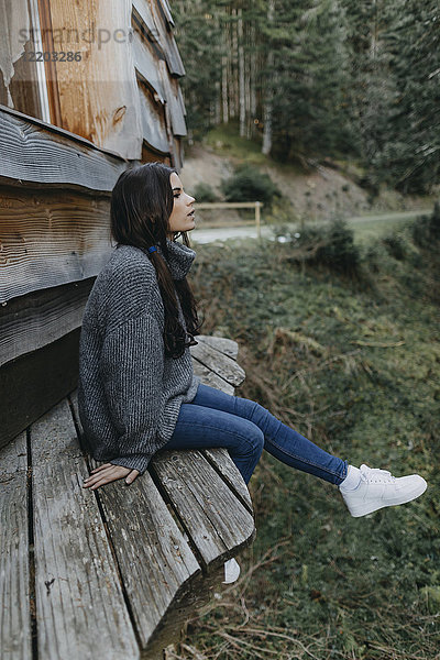 Junge Frau sitzend in einem Holzhaus in der Natur