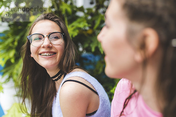 Fröhliches Teenagermädchen mit Zahnspange und Brille beim Anblick eines Freundes