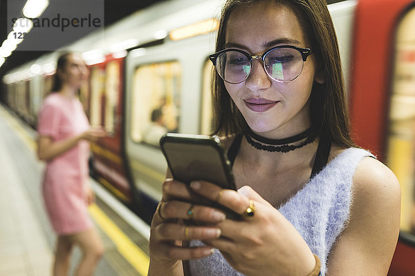 Teenager-Mädchen mit Handy in der U-Bahn-Station