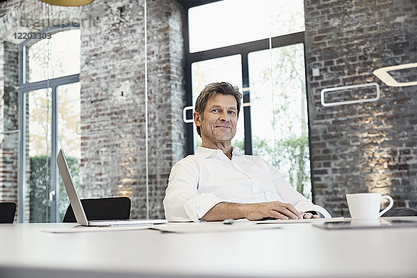Portrait eines reifen Geschäftsmannes mit Laptop im modernen Büro