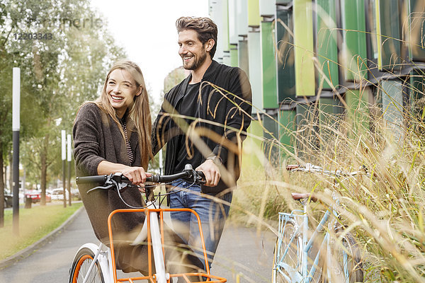 Lächelndes Paar mit Fahrrädern auf der Straße