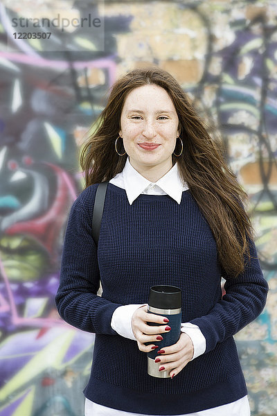 Deutschland  Berlin  Porträt eines lächelnden Teenagermädchens vor Graffiti