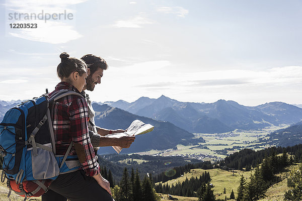 Österreich  Tirol  junges Paar auf der Karte in der Berglandschaft