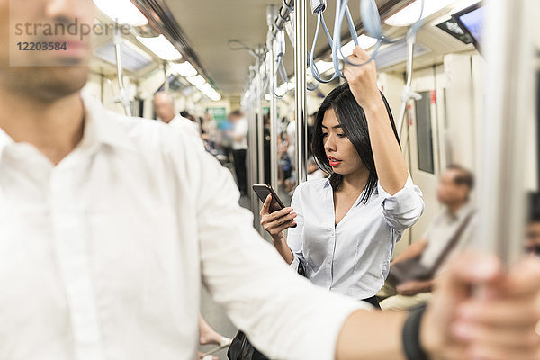 Geschäftsfrau mit Handy in der U-Bahn