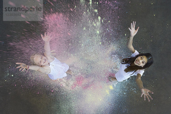 Zwei Freunde werfen Farbpulver in die Luft.