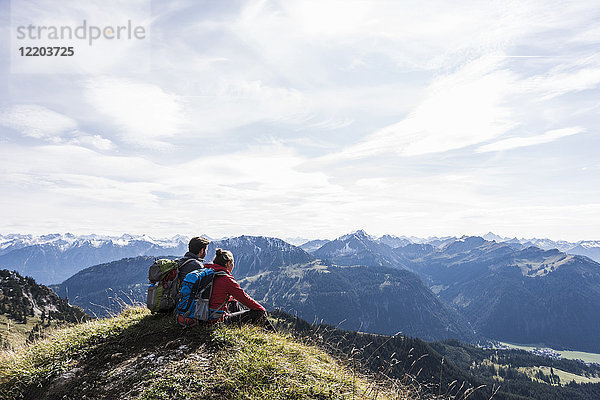 Österreich  Tirol  junges Paar in Berglandschaft sitzend mit Blick auf die Landschaft