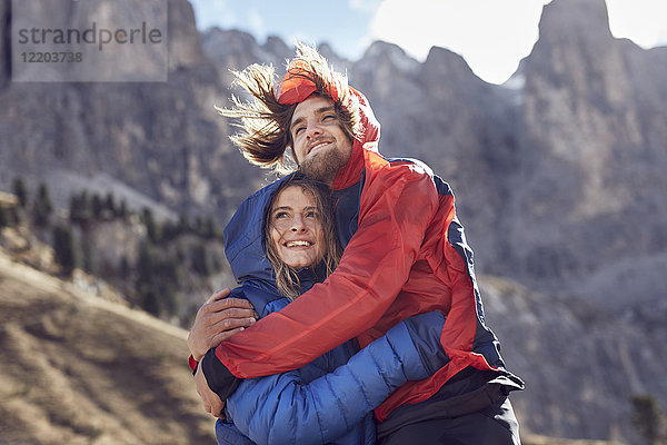 Glückliches junges Paar  das sich in windigen Bergen umarmt.