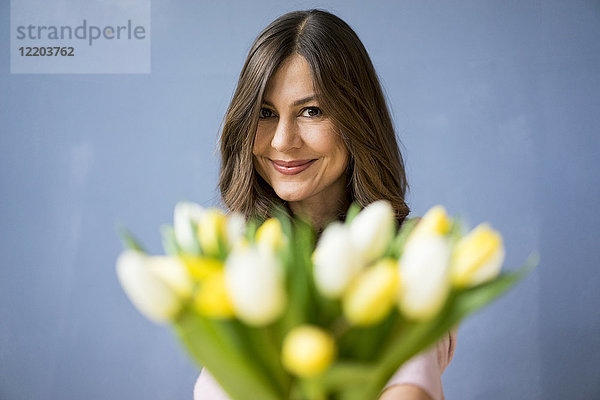 Porträt einer lächelnden Frau mit Tulpenstrauß