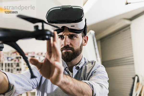 Mann mit VR-Brille hält Drohne