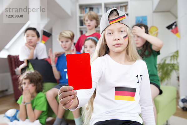 Mädchen zeigt rote Karte vor Freunden  schaut sich die Fußballweltmeisterschaft an