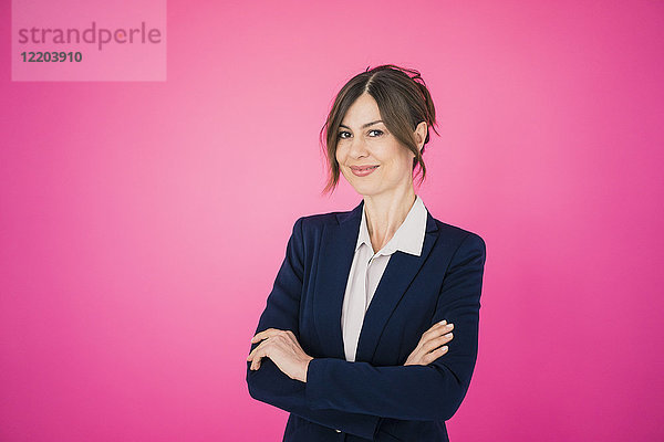 Porträt einer selbstbewussten Geschäftsfrau vor rosa Wand