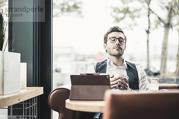 Junger Mann in einem Café mit Tablettentasse Kaffee zum Entspannen