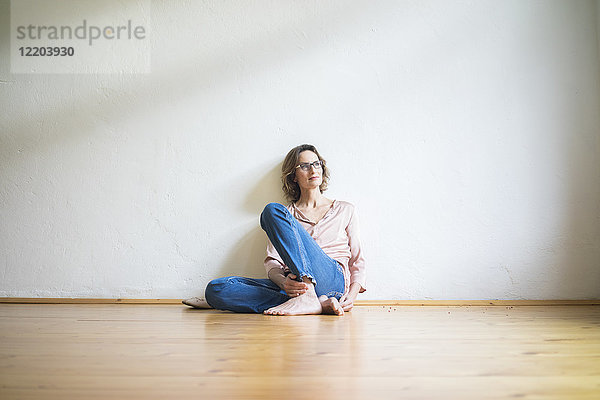 Reife Frau  die auf dem Boden in einem leeren Raum sitzt und nachdenkt.