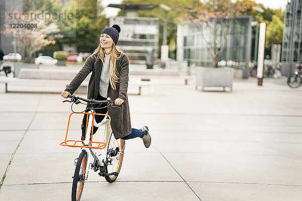 Glückliche Frau beim Fahrradfahren in der Stadt