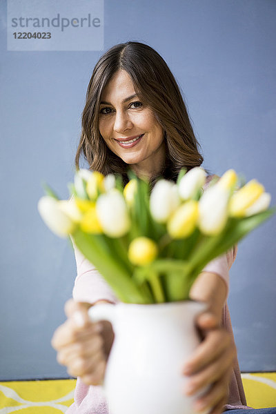 Porträt einer lächelnden Frau mit Tulpenstrauß im Glas