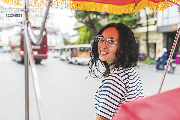 Vietnam  Hanoi  Porträt einer lächelnden jungen Frau auf einer Rikscha in der Stadt