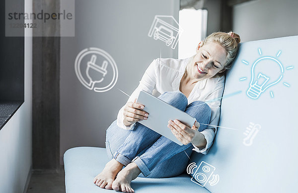 Frau sitzt im Büro und benutzt ein digitales Tablett  um sein intelligentes Zuhause fernzusteuern.