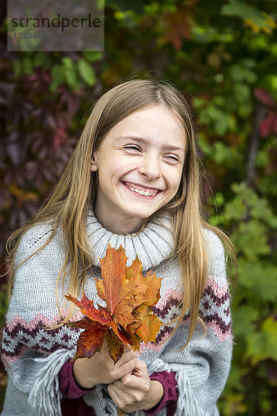 Porträt eines lachenden Mädchens mit herbstlichen Blättern