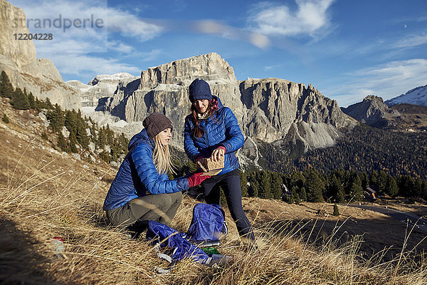 Zwei junge Frauen beim Wandern in den Bergen bei einer Pause