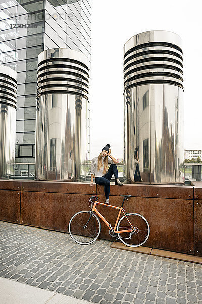 Junge Frau mit Fahrrad bei einer Pause in der Stadt