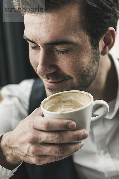 Entspannter junger Mann trinkt eine Tasse Kaffee.