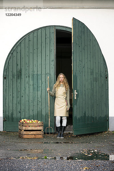 Frau auf einem Bauernhof stehend an einer Kiste mit Äpfeln
