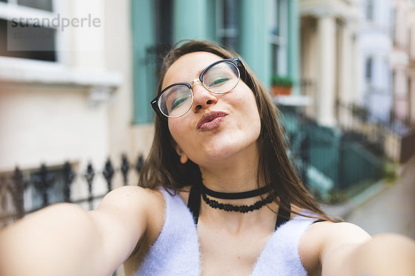 Fröhliches Teenagermädchen in der Stadt mit einem Selfie