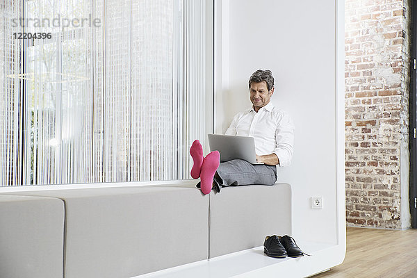 Geschäftsmann mit rosa Socken mit Laptop im Büro
