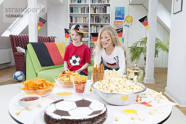 Geschwister beim Fußball-WM schauen mit Süßigkeiten und Snacks