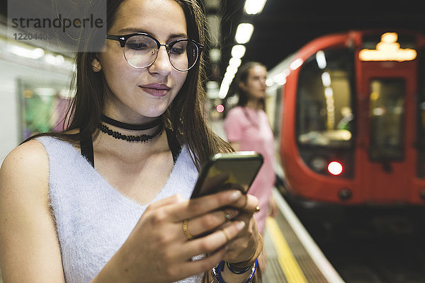 Teenager-Mädchen mit Handy in der U-Bahn-Station