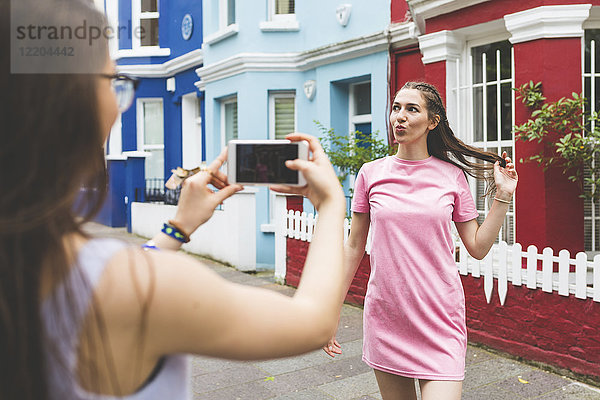 Teenagermädchen macht Handyfoto von junger Frau in der Stadt