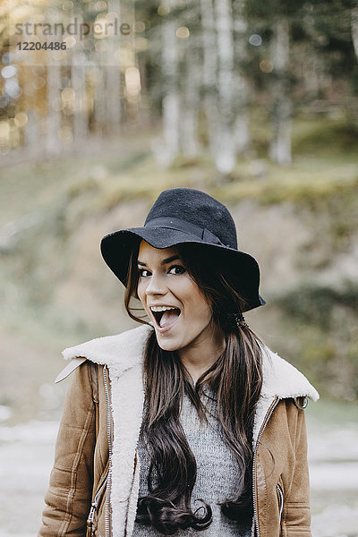 Porträt einer glücklichen jungen Frau mit flauschigem Hut in der Natur
