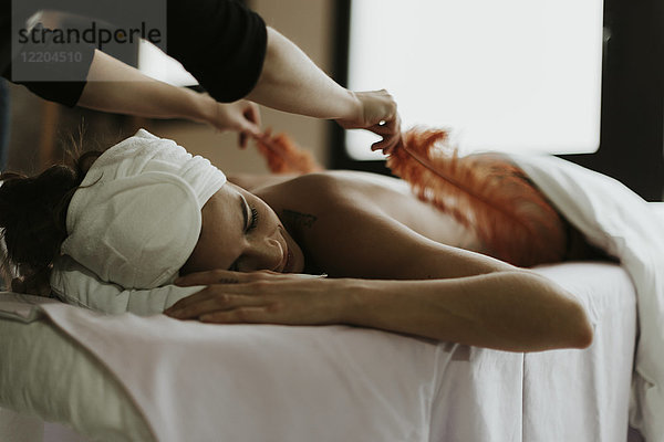 Junge Frau erhält eine Massage mit Federn in einem Spa