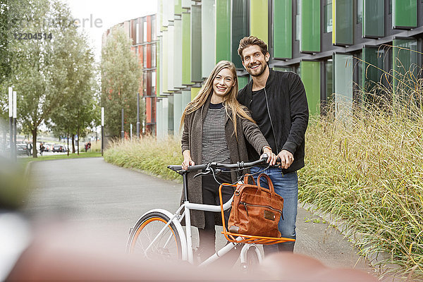 Porträt eines lächelnden Paares mit Fahrrad auf einem Weg