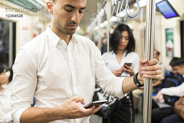 Geschäftsmann und Geschäftsfrau mit Mobiltelefonen in der U-Bahn