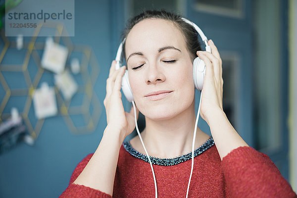 Porträt einer Frau mit geschlossenen Augen Musik hören mit Kopfhörer