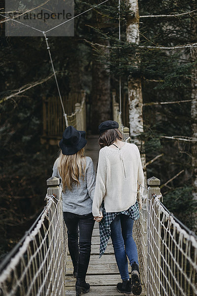 Zwei glückliche junge Frauen  die zusammen auf einer Aufhängung laufen.