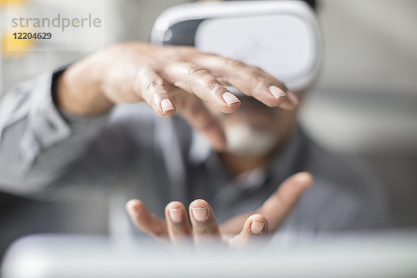 Mann formt mit den Händen mit VR-Brille im Büro