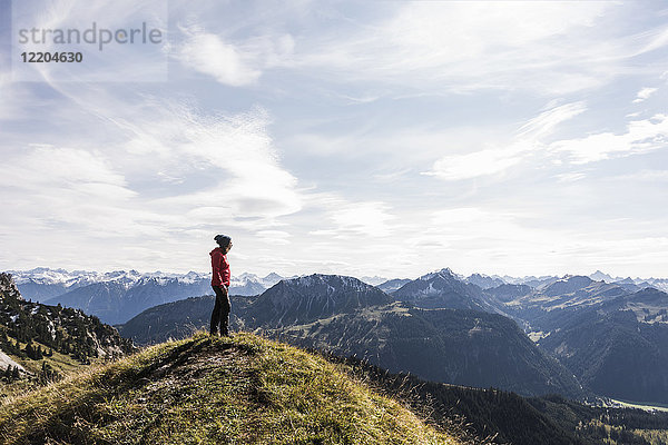 Österreich  Tirol  junge Frau in der Berglandschaft stehend mit Blick auf die Landschaft