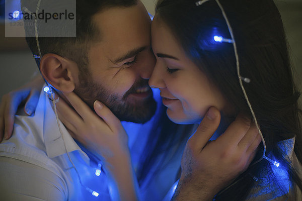 Lichterkette auf einem sich umarmenden kaukasischen Paar