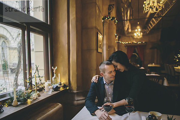 Kaukasisches Paar trinkt Wein und umarmt sich im Restaurant