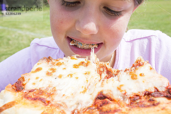 Nahaufnahme eines kaukasischen Mädchens mit Zahnspange  das in eine Pizza beißt