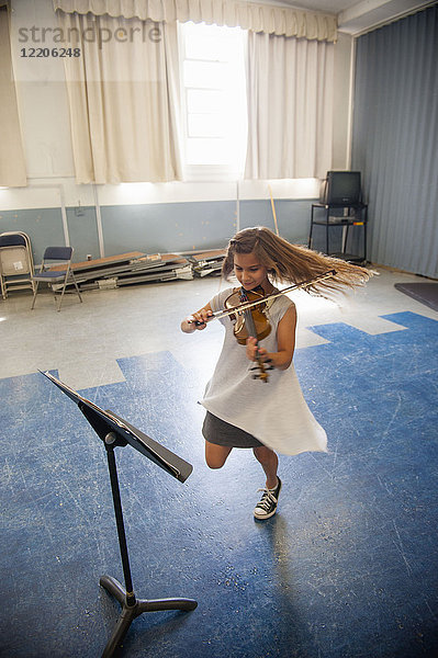 Kaukasisches Mädchen übt Geige und tanzt