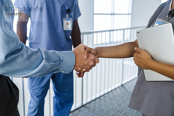 Arzt und Krankenschwester schütteln Hände in der Nähe des Geländers