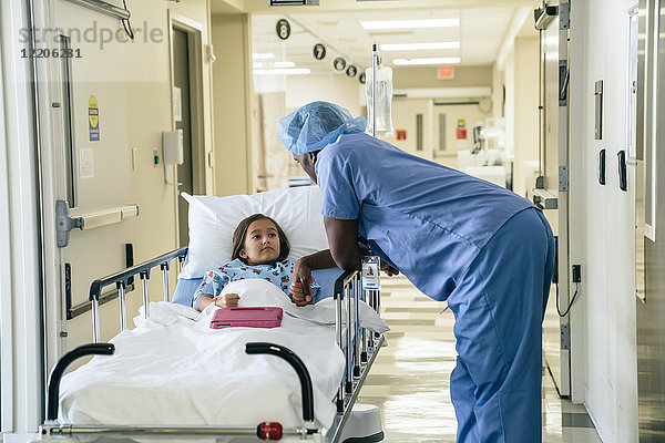 Arzt hält die Hand eines Mädchens auf einer Krankenhausbahre