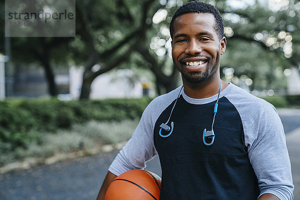 Porträt eines lächelnden schwarzen Mannes  der einen Basketball hält
