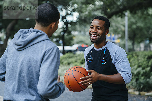 Lächelnde schwarze Männer spielen Basketball