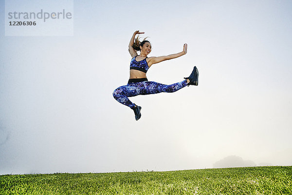 Gemischtrassige Frau beim Training und Springen im Feld
