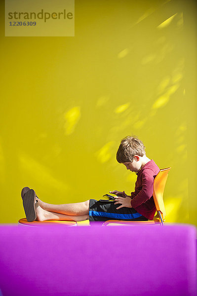 Kaukasischer Junge  der sich entspannt und ein digitales Tablet liest